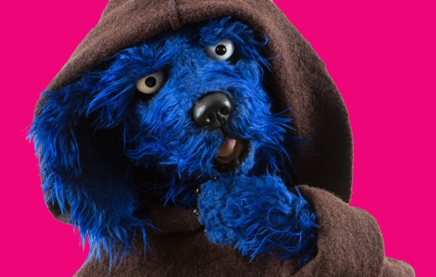 Das Bild zeigt Tölpel, den Protagonisten der Mitmachausstellung "Der Mönch war's". Es ist ein blauer Plüschhund, der eine Mönchskutte trägt.